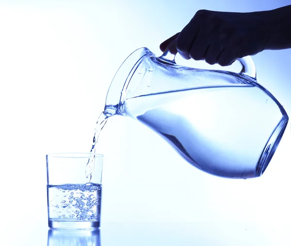 Verser de l'eau dans du verre sur fond bleu — Photo