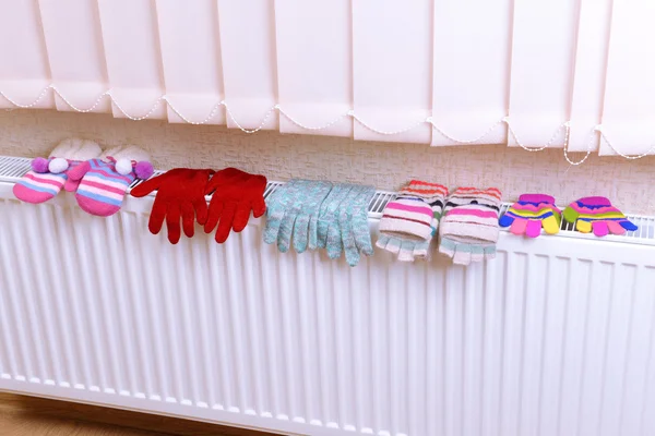 Knitted gloves drying on heating radiator — Stock Photo, Image