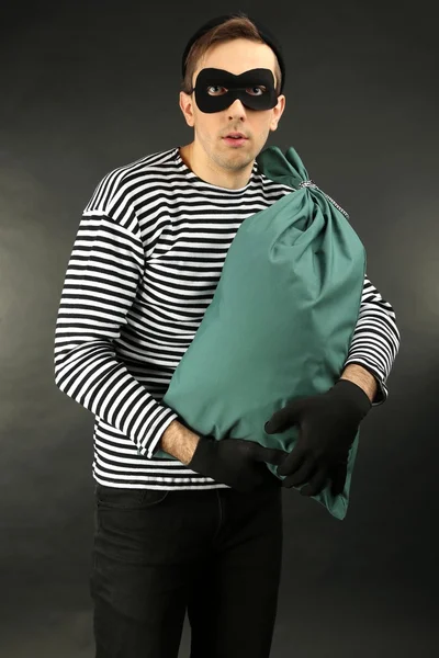 Thief with bag on dark background — Stock Photo, Image