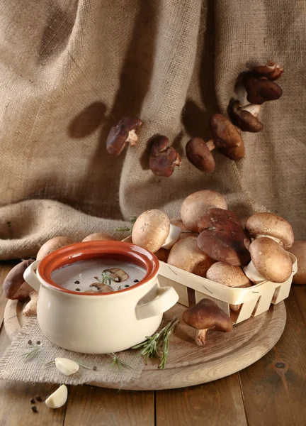 Mushroom soup in pot, on wooden table, on sackcloth background — Stock Photo, Image