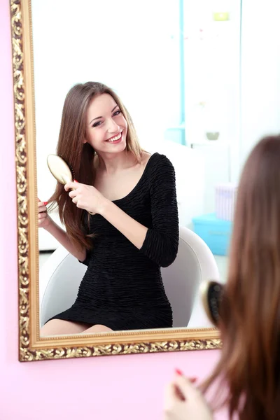 Giovane bella donna che fa acconciatura vicino specchio — Foto Stock