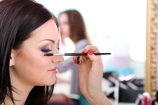Mulher jovem estilista fazendo maquiagem menina bonita no salão de beleza — Fotografia de Stock
