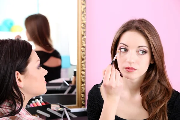 Young woman stylist doing makeup beautiful girl in beauty salon — Stock Photo, Image