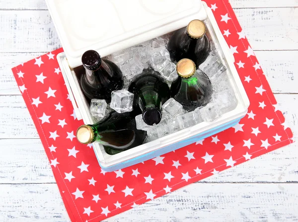 Pecho de hielo lleno de bebidas en botellas en servilleta de color, sobre fondo de madera —  Fotos de Stock