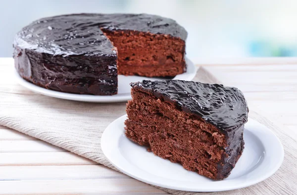 Delicioso pastel de chocolate en el plato en la mesa sobre fondo claro — Foto de Stock