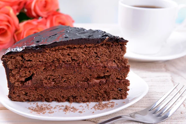 Köstlicher Schokoladenkuchen auf Teller auf Tisch vor hellem Hintergrund — Stockfoto