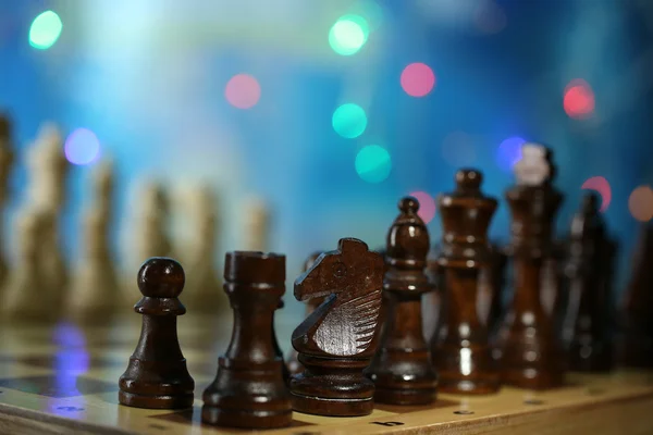Piezas de ajedrez a bordo sobre fondo brillante — Foto de Stock