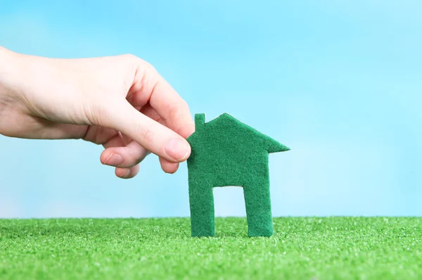 Little paper house in hand on green grass on bright background — Stock Photo, Image