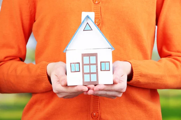 Papier huisje in de hand close-up, op lichte achtergrond — Stockfoto