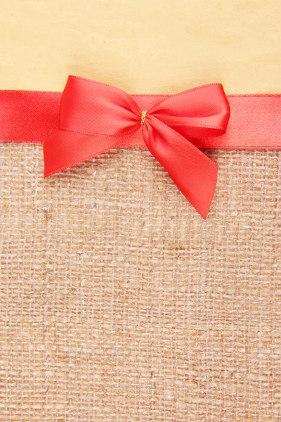 Sackcloth with color ribbon and bow on color paper background — Stock Photo, Image