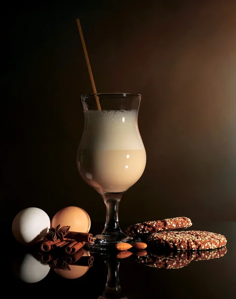 蛋奶酒含有香料和彩色背景上的橙色 — 图库照片