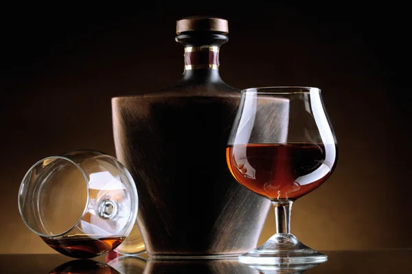 Vasos de brandy y botella sobre fondo marrón — Foto de Stock