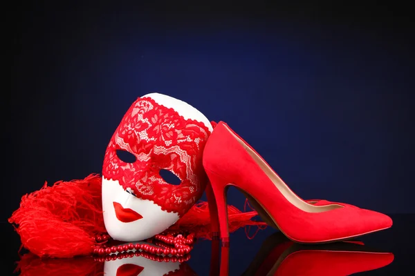 Beautiful red female shoes and carnival mask, on blue background — Stock Photo, Image