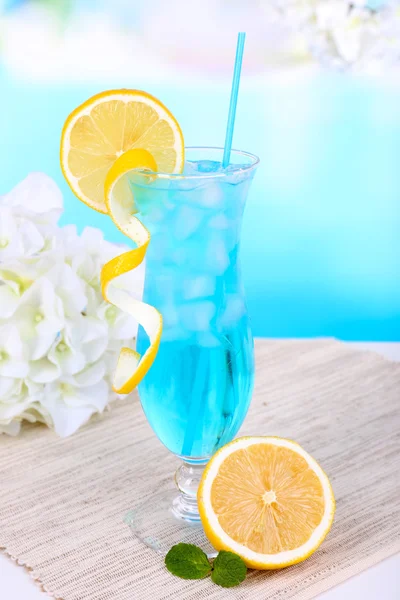 Glass of cocktail on table on light blue background — Stock Photo, Image