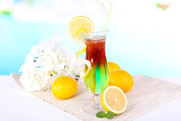 Glass of cocktail on table on light blue background — Stock Photo, Image