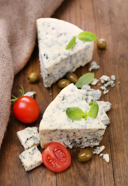 Schmackhafter Blauschimmelkäse mit Tomaten, Oliven und Basilikum, auf Holztisch — Stockfoto