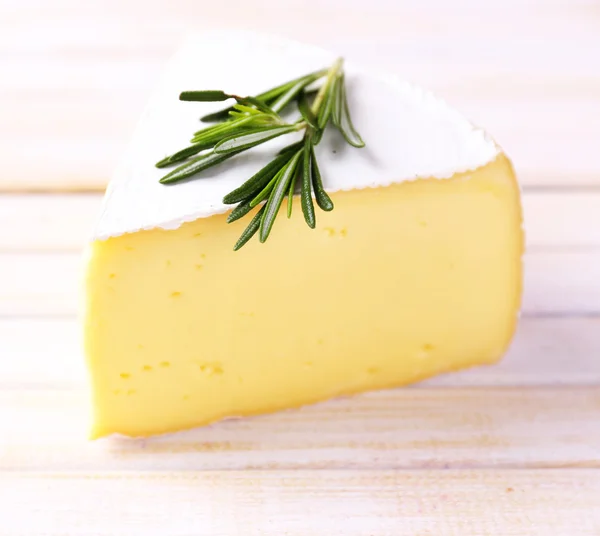 Välsmakande camembert ost med rosmarin, på träbord — Stockfoto