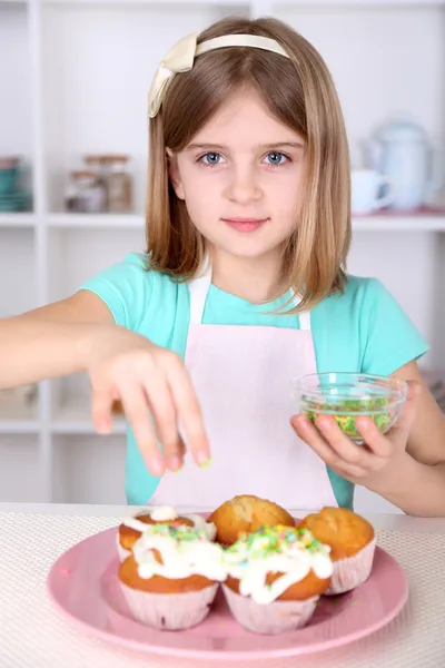 Little girl decorating cupcakes in kitchen at home — Stock Photo, Image