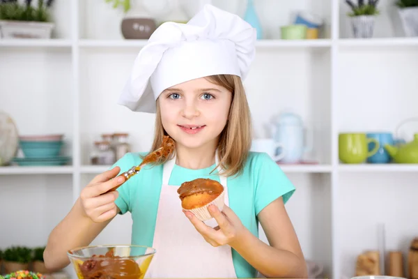 自宅の台所でカップケーキを飾る小さな女の子 — ストック写真