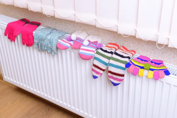 Knitted gloves drying on heating radiator — Stock Photo, Image