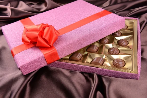 Delicious chocolates in box on brown background — Stock Photo, Image