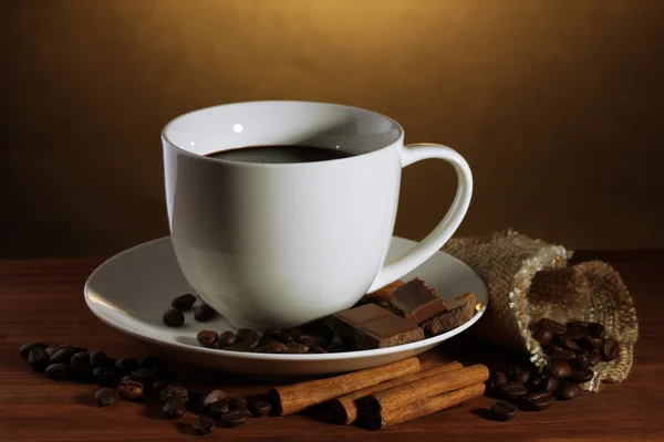 杯咖啡和咖啡豆、 肉桂棒和巧克力棕色背景上的木桌上 — 图库照片