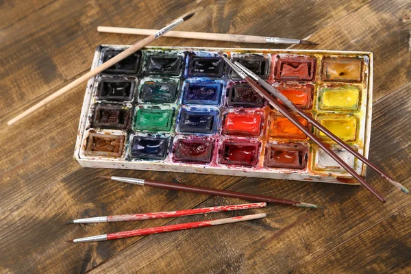 Colourful watercolors and brushes on wooden background — Stock Photo, Image