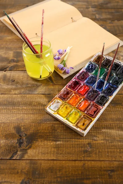 Komposition mit farbenfrohen Aquarellen, Pinseln und Skizzen auf Holzgrund — Stockfoto