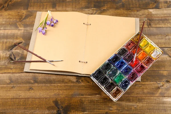 Renkli suluboya, fırçalar ve ahşap zemin üzerinde sketcher kompozisyonu — Stok fotoğraf