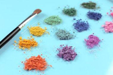 Gökkuşağı göz farı ve profesyonel makyaj fırçası mavi zemin üzerine ezilmiş