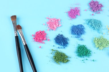 Gökkuşağı göz farı ve profesyonel makyaj fırçası mavi zemin üzerine ezilmiş