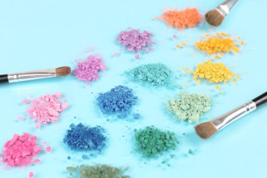 Gökkuşağı göz farı ve profesyonel makyaj fırçası mavi zemin üzerine ezilmiş