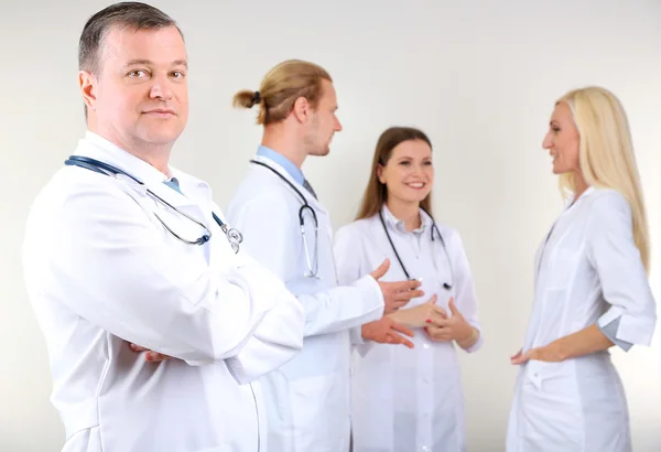 Lekarz stoi przed współpracowników na szarym tle — Zdjęcie stockowe