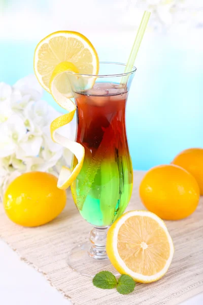 Glass of cocktail on table on light blue background — Stock Photo, Image