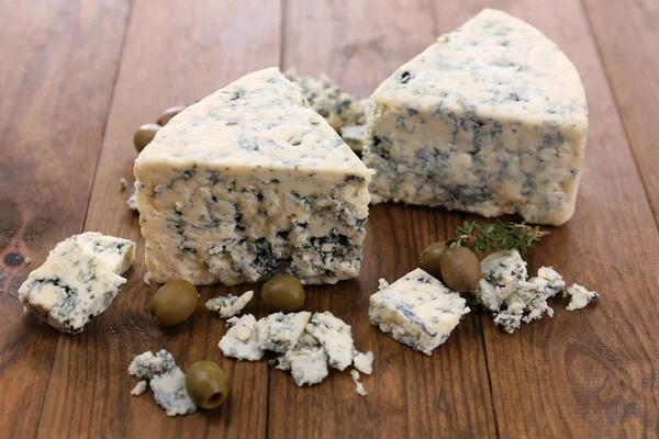 Tasty blue cheese with olives, on wooden table — Stock Photo, Image