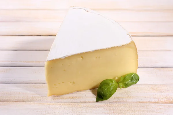 Tasty Camembert cheese with basil, on wooden table — Stock Photo, Image