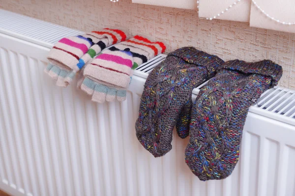 Knitted gloves drying on heating radiator — Stock Photo, Image