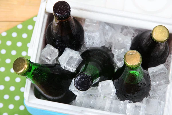 Caixa de gelo cheia de bebidas em garrafas em guardanapo de cor, em fundo de madeira — Fotografia de Stock