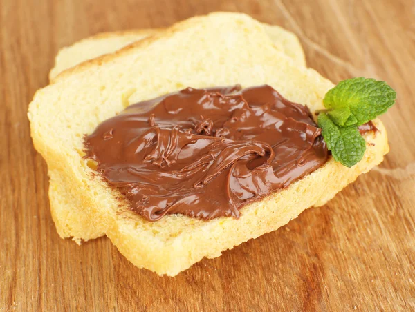 Brood met zoete chocolade hazelnoot verspreid over houten achtergrond — Stockfoto