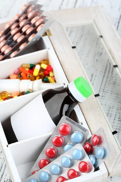 Medical pills, ampules in wooden box, on color background — Stock Photo, Image