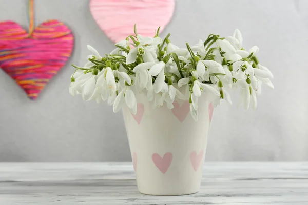 Krásný sněženky v váza s srdce na šedém pozadí — Stock fotografie