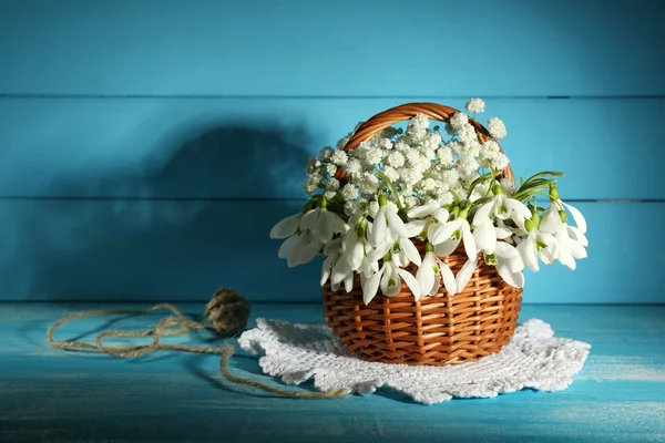 Schöne Schneeglöckchen im Korb auf blauem Holztisch — Stockfoto