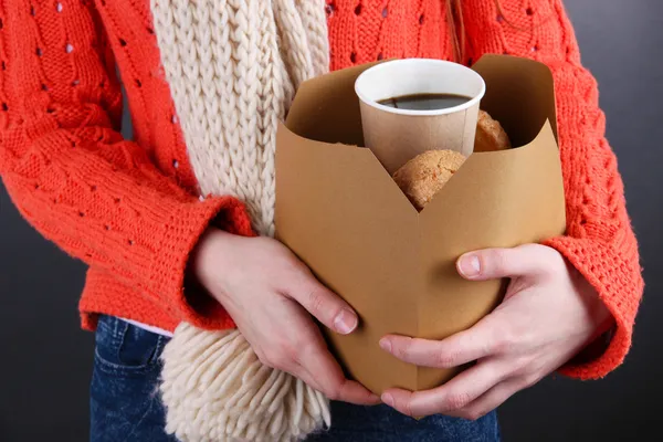 Femme tient boîte avec café et biscuits sur fond noir — Photo