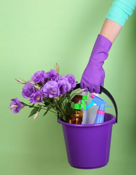 Huisvrouw houden emmer met reinigingsapparatuur op kleur achtergrond. conceptuele foto van lente schoonmaak. — Stockfoto