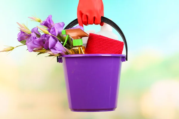 Hausfrau hält Eimer mit Reinigungsgeräten auf hellem Hintergrund. Konzeptfoto vom Frühjahrsputz. — Stockfoto