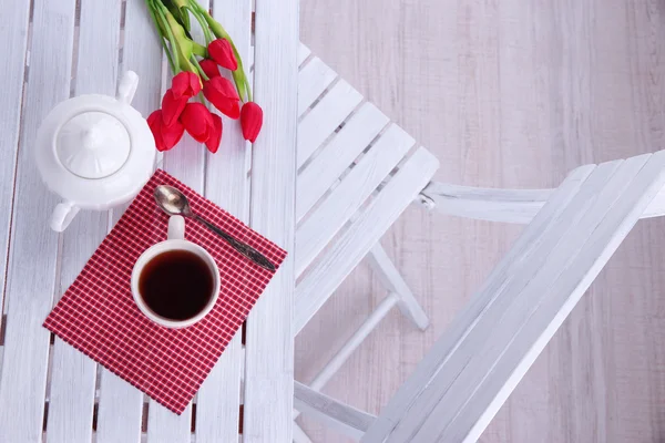 Samenstelling met kop van warme dranken, kaars en bloemen op houten tafel achtergrond — Stockfoto