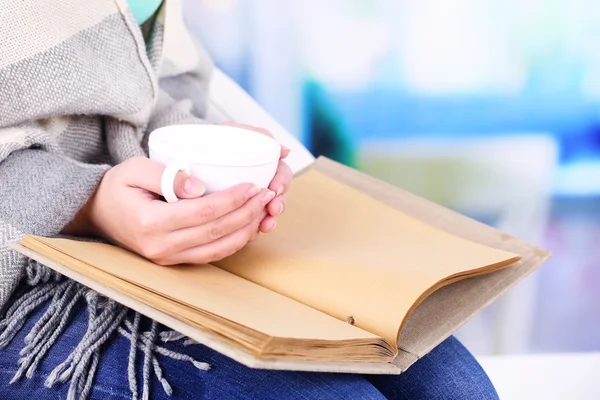 Vrouw leest boek en drinken koffie of thee, close-up — Stockfoto