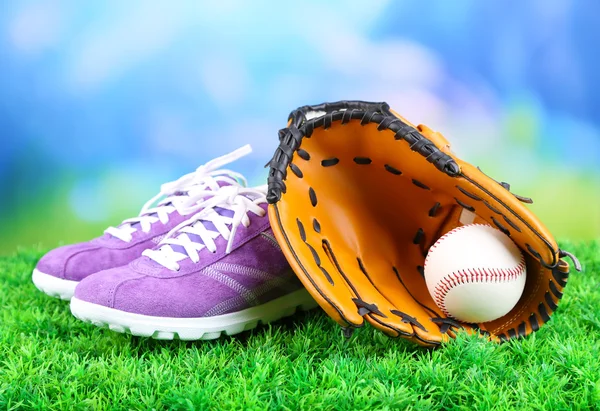 Hermosos zapatos de goma y pelota de béisbol, guante sobre hierba verde, sobre fondo brillante —  Fotos de Stock