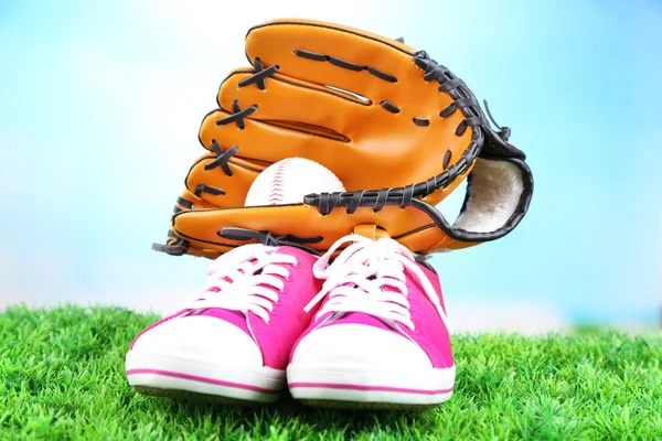 Hermosos zapatos de goma y pelota de béisbol, guante sobre hierba verde, sobre fondo brillante — Foto de Stock