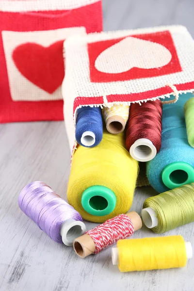 Bobines colorées de fil dans le sac, sur fond en bois — Photo